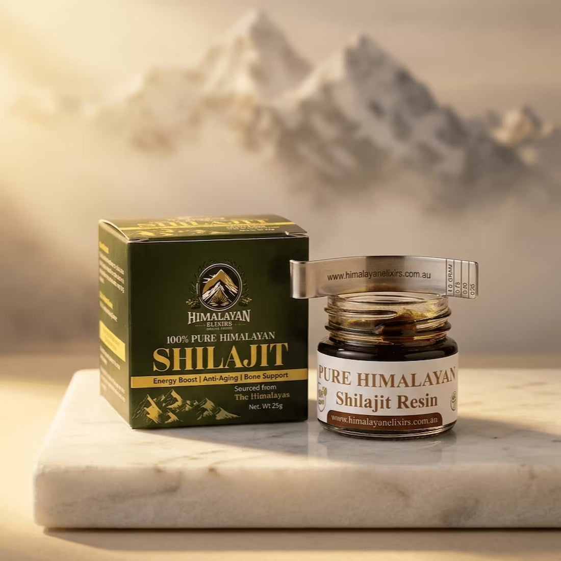 Jar of Himalayan Elixirs pure Shilajit resin with its packaging box and spoon arranged on a natural stone surface, illuminated by warm golden light with softly blurred Himalayan mountain peaks in the background now in Australia