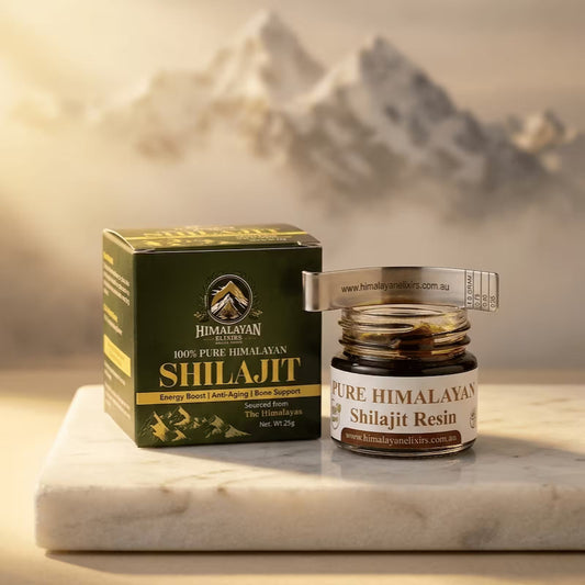 Jar of Himalayan Elixirs pure Shilajit resin with its packaging box and spoon arranged on a natural stone surface, illuminated by warm golden light with softly blurred Himalayan mountain peaks in the background now in Australia