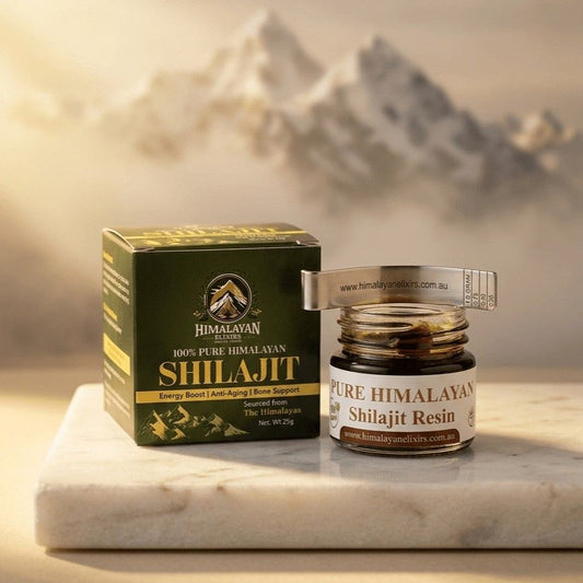 Jar of Himalayan Elixirs pure Shilajit resin with its packaging box and spoon arranged on a natural stone surface, illuminated by warm golden light with softly blurred Himalayan mountain peaks in the background now in Australia