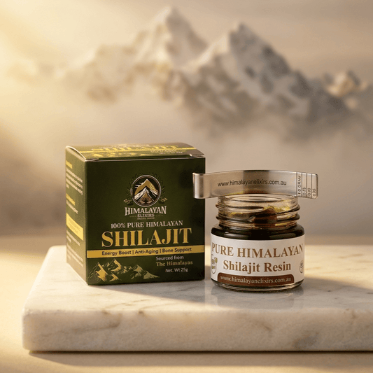 Jar of Himalayan Elixirs pure Shilajit resin with its packaging box and spoon arranged on a natural stone surface, illuminated by warm golden light with softly blurred Himalayan mountain peaks in the background now in Australia